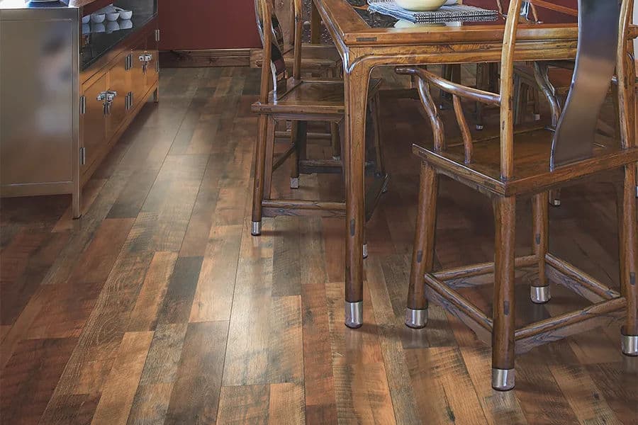 Wood dining table and chairs on rustic hardwood floor in cozy kitchen setting.