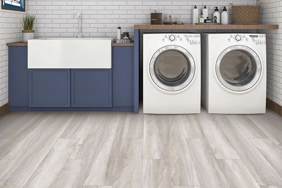 Modern laundry room featuring white appliances, farmhouse sink, and stylish blue cabinetry.